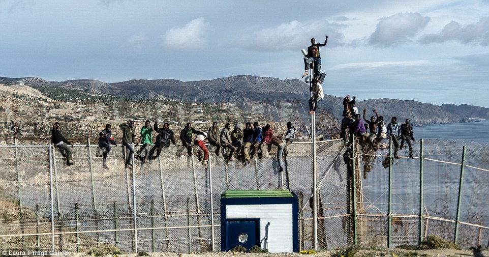 Effective?: Migrants claim to the top of the fence which runs along the border of Morocco and the North African Spanish enclave of Melilla