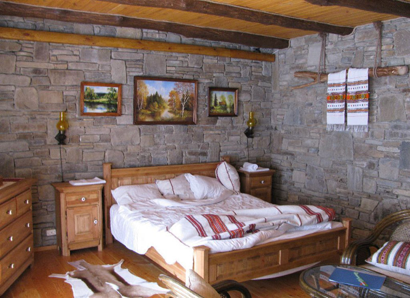 Натуральный камень и потолочные балки в интерьере спальни “шале”